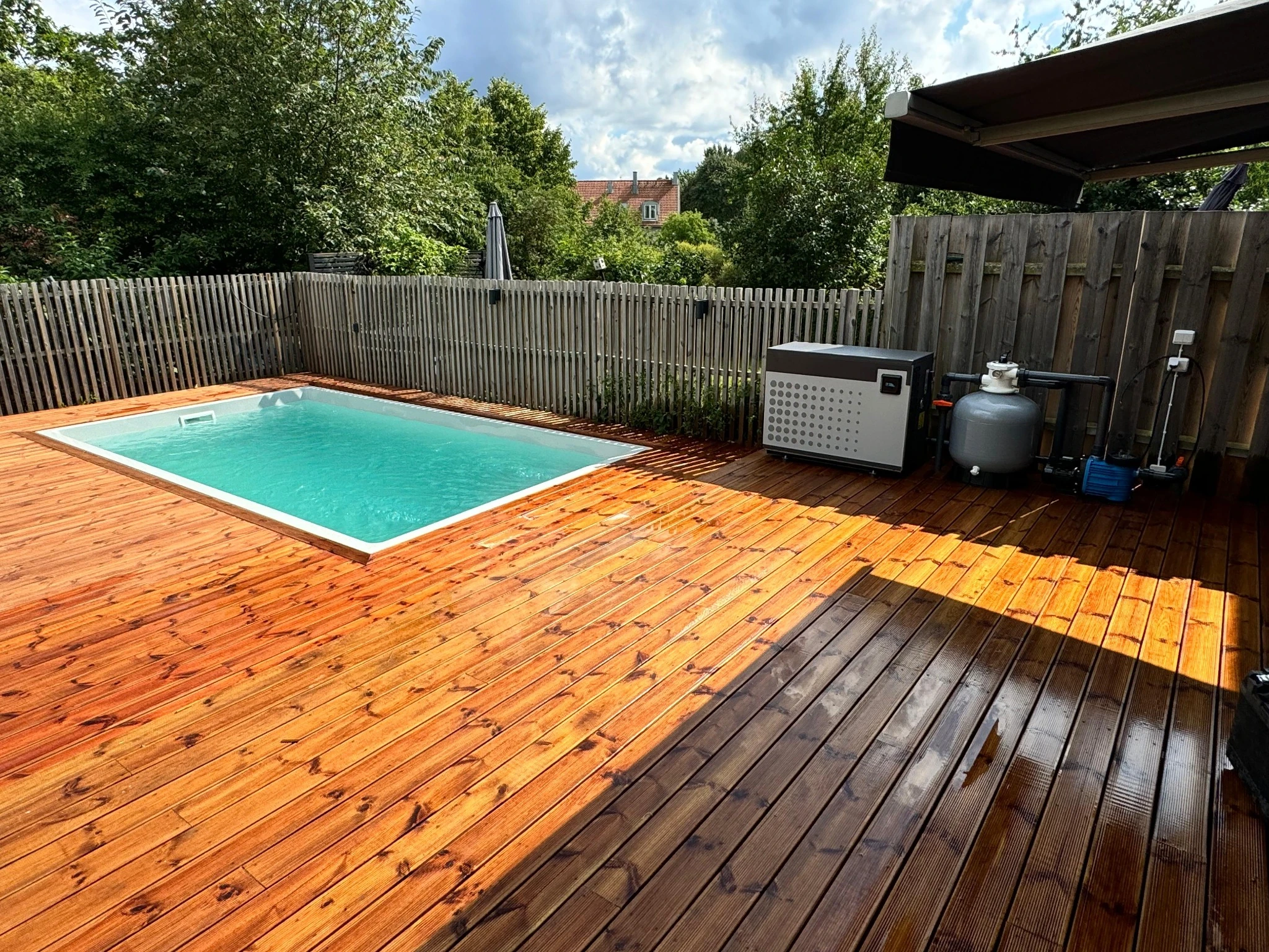 A Poolworks swimming pool set into a sunny timber deck beside its equipment